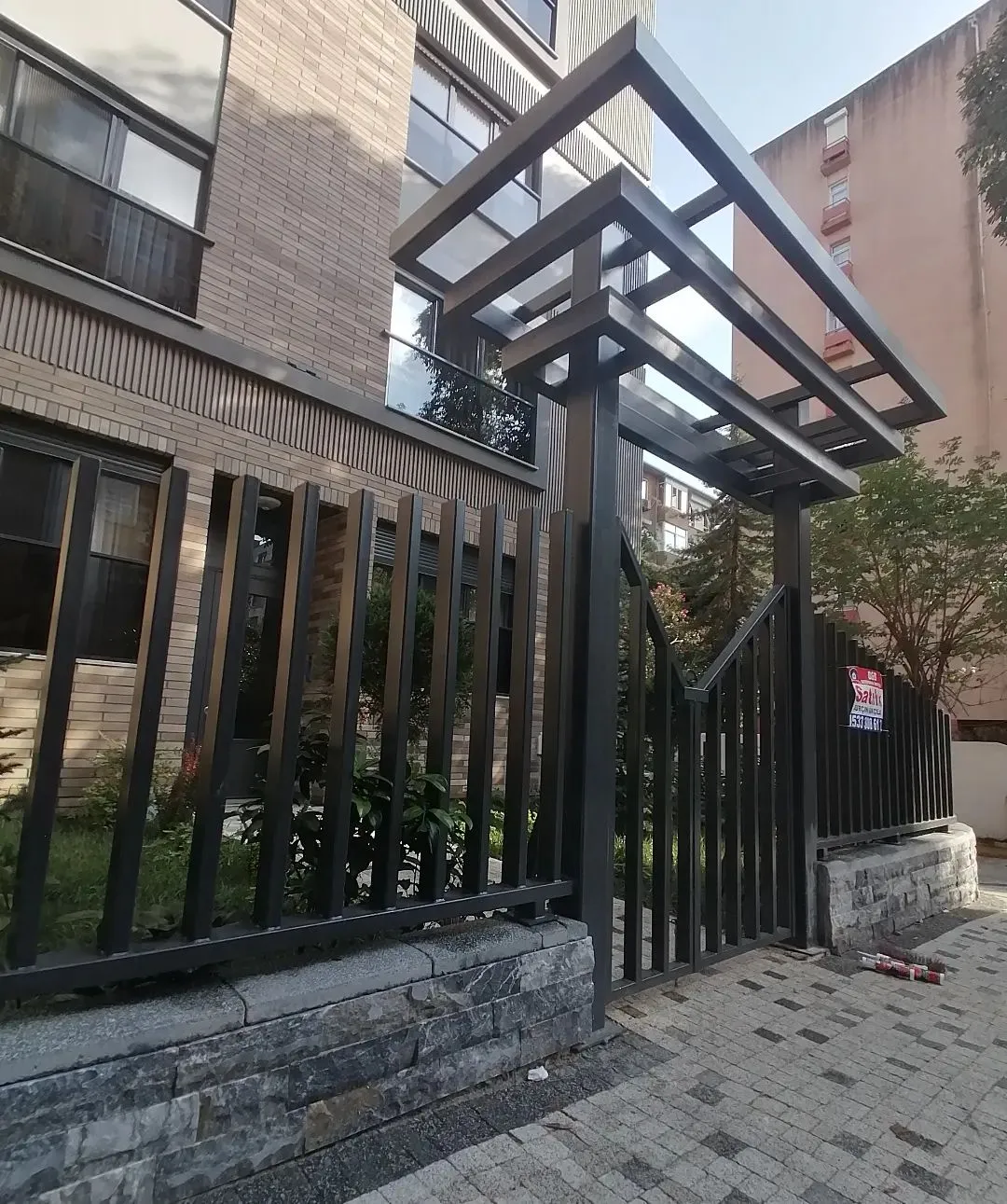 Apartman girişinde demir saçak ve dikey çubuklu çit