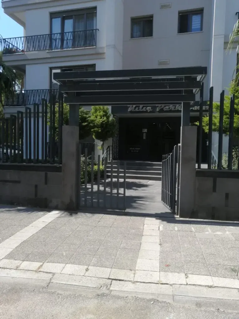 Apartman girişinde siyah metal saçak ve dikey çubuklu çit