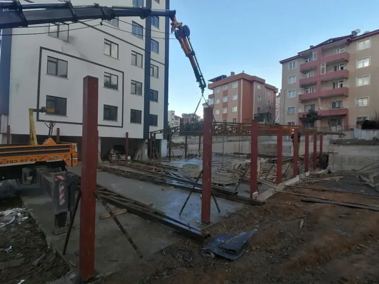 Vinçle yerleştirilen kırmızı astarlı demir kolonlar