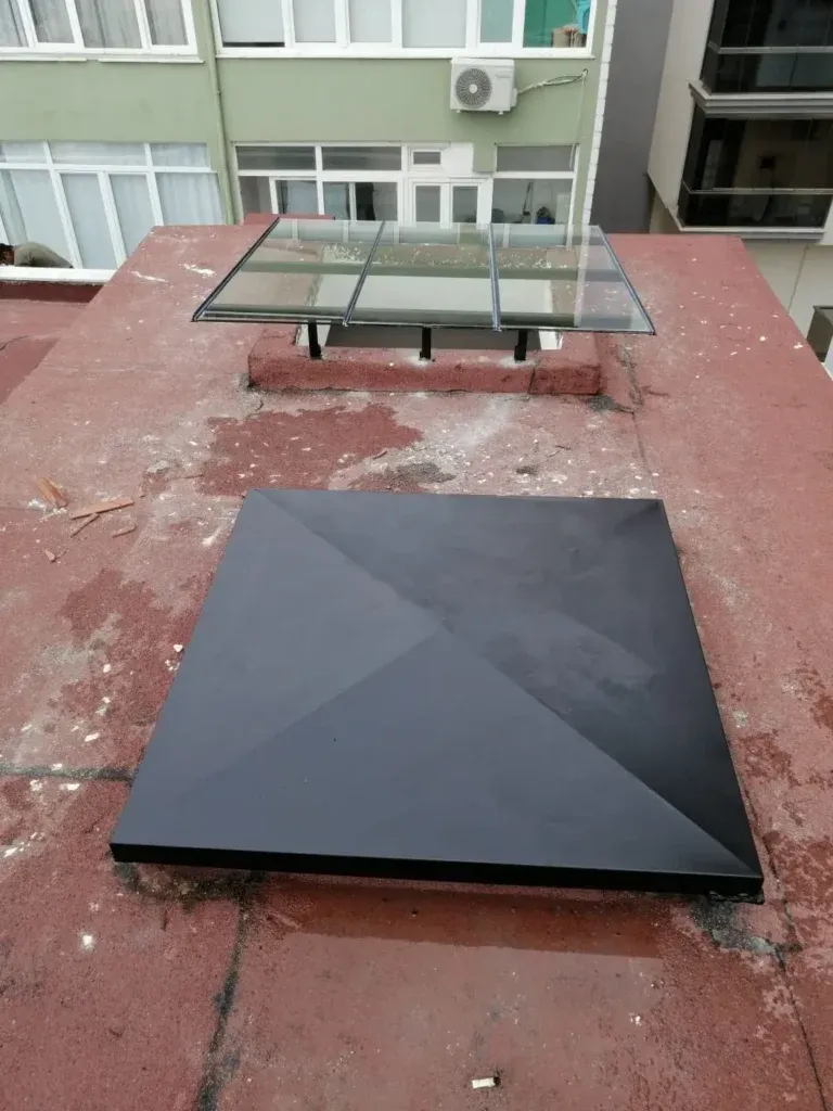 Teras çatısında siyah metal baca şapkası ve cam çatı penceresi