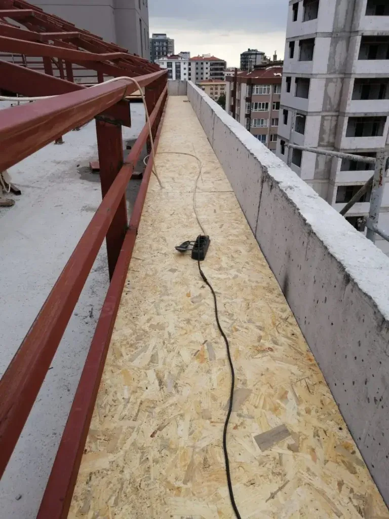Çatı kenarında kırmızı astarlı demir dikmeler ve OSB levha kaplama