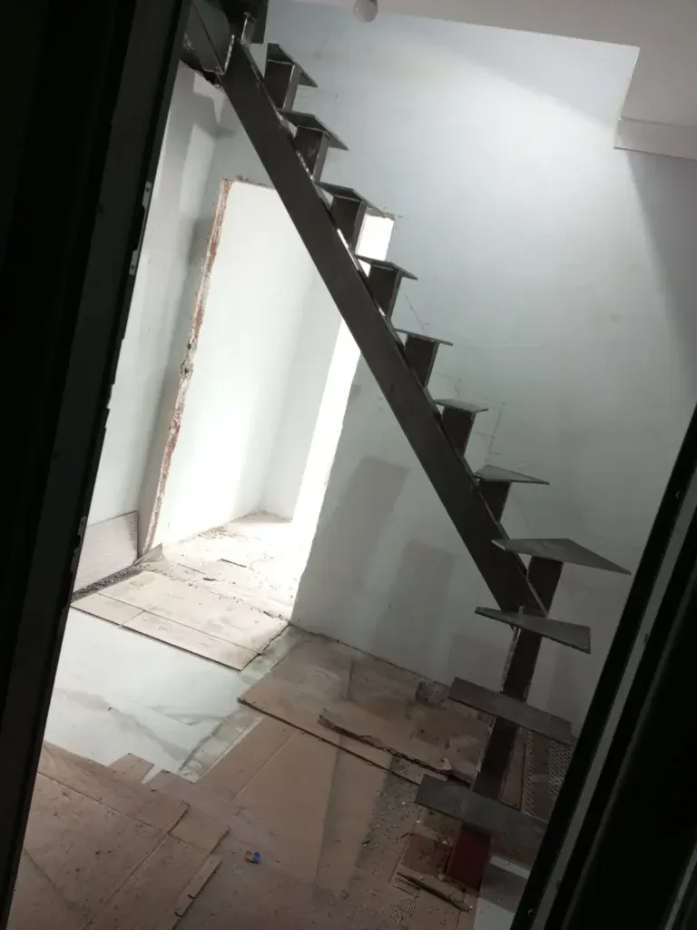 Beyaz duvar boyunca yükselen tek kirişli siyah metal merdiven
