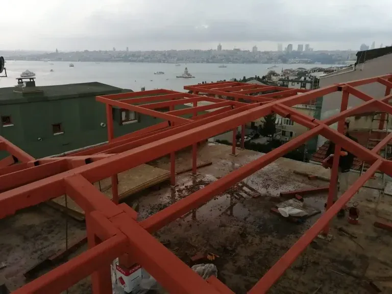 Deniz manzaralı bir çatıda kırmızı astarlı demir iskelet