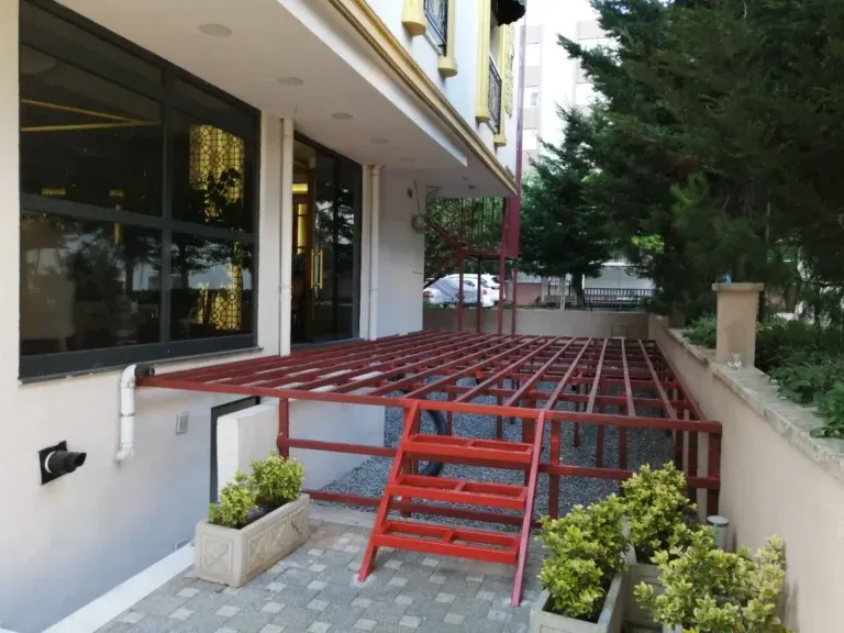 Bina önünde kırmızı astarlı demir teras iskeleti ve merdiveni