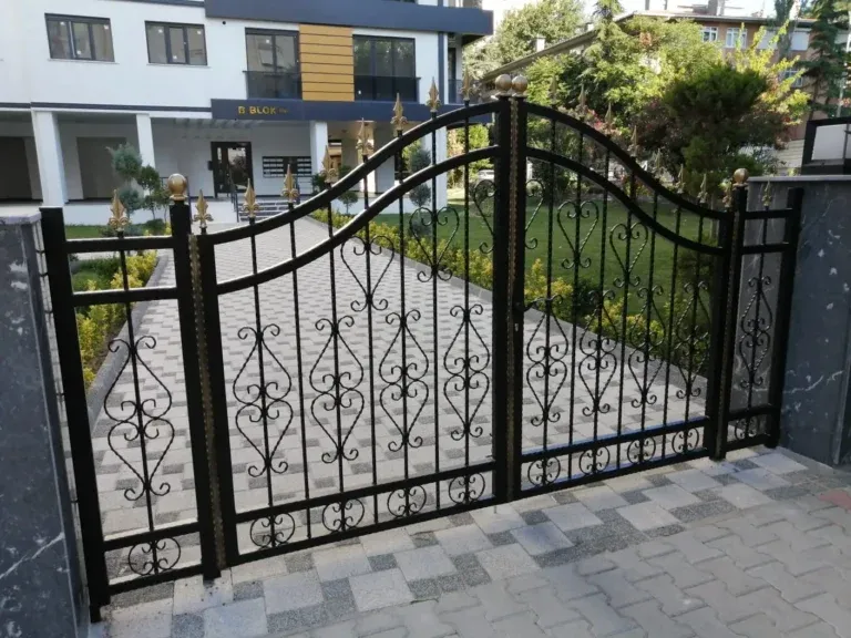 Bahçe girişinde süslemeli, kemerli siyah ferforje kapı