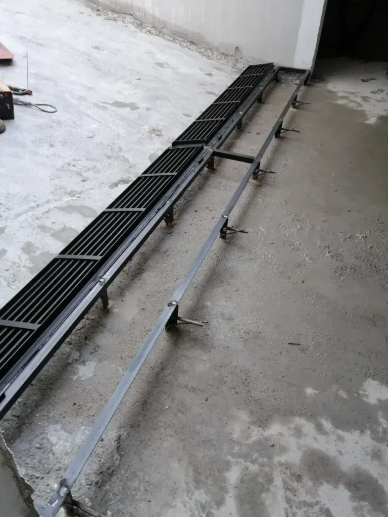 Terasta zemine yerleştirilen siyah ızgaralı metal kanal